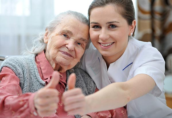 Caregiver with senior woman with thumbs up