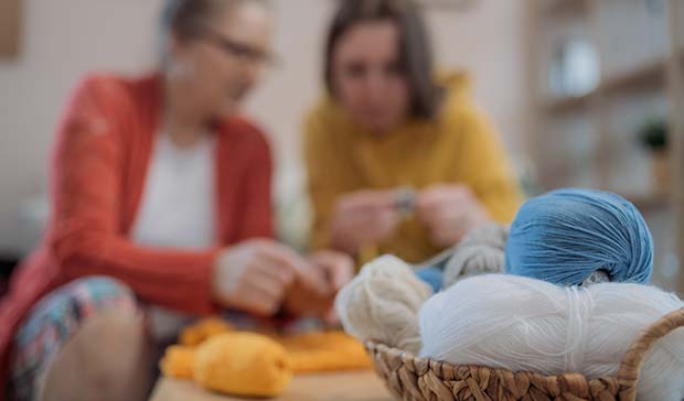 elderly woman and caregiver doing crafts with yarn