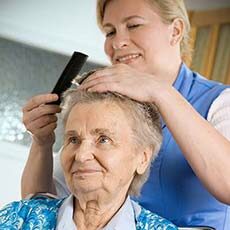 Caregiver combing hair of senior woman