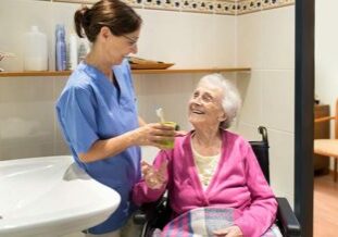 Caregiver helping smiling senior woman brush her teeth