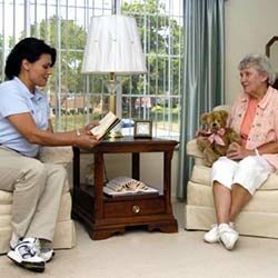 In home caregiver reading to senior woman