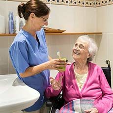 Caregiver helping senior woman with grooming