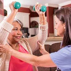 Caregiver helping senior woman exercise
